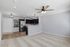 Bright open-plan living area featuring a modern kitchen with navy cabinets, stainless steel appliances, and elegant lighting.