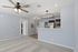 Modern interior with sleek ceiling fans, elegant lighting, and an open kitchen layout featuring stylish cabinetry and stainless steel appliances.