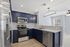 Modern kitchen with sleek navy cabinets, spacious countertops, stainless steel appliances, and stylish lighting.