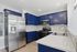 Modern kitchen with vibrant blue cabinets, stainless steel appliances, and sleek white countertops.