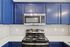 Modern kitchen featuring vibrant blue cabinetry, sleek stainless-steel appliances, and a stylish hexagonal tile backsplash.
