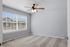 Bright bedroom with plush carpet, large window with blinds, and modern ceiling fan offering a cozy and inviting atmosphere.