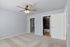 Modern bedroom featuring soft carpet flooring, a ceiling fan, and a bright en-suite bathroom with stylish tile work.