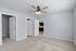Bright and spacious room with fresh carpet and elegant ceiling fan, leading to a sleek kitchen with polished wooden floors.