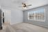 Bright bedroom with modern ceiling fan, large window offering ample natural light, and freshly carpeted floor.