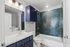 Contemporary bathroom with chic herringbone teal tiles, elegant white countertop, and stylish navy cabinetry.