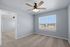 Bright and spacious bedroom with plush carpet, modern ceiling fan, and large window offering a serene view.