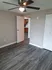 Bedroom in one bedroom apartment with a double door leading to the closet and gray VCT flooring. A ceiling fan with a light is also pictured