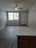 Living room in the Hampton floorplan. Picture is from the open kitchen showing the front window with light shining through. The floor is a gray VCT floor and there is a small ledge by the front window.