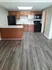 Kitchen in the one bedroom floorplan showing an open concept with light brown cabinets, black appliances and light gray countertops