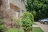 Exterior view of a cozy apartment complex with lush greenery and neatly parked cars.