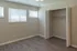 Bright and inviting bedroom with sleek laminate flooring, generous closet space, and abundant natural light from three large windows.