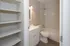Bright and modern bathroom featuring elegant marble walls, a sleek vanity, and ample shelving for storage.