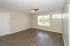 Bright, spacious living room with modern wood flooring and large windows offering a serene garden view.