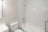 Elegant bathroom with a sleek white bathtub, modern fixtures, and stylish marble-tiled walls.