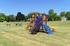 Charming playground with colorful slides and climbing structures set in a spacious, sunny grassy area, perfect for outdoor family fun.