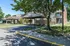 Charming apartment complex featuring brick exteriors and covered parking, surrounded by lush greenery and shade trees.