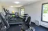 Bright and modern apartment gym with state-of-the-art cardio equipment, free weights, and vibrant exercise balls, offering a refreshing workout space with large windows for natural light.