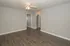 Spacious room with modern grey walls and pristine dark wood flooring, featuring a ceiling fan for comfort and style.