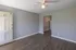 Inviting living room with sleek gray walls and stylish wooden flooring, complemented by a ceiling fan and adjoining open entrance to the kitchen area.
