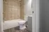 Modern bathroom with elegant tiled walls and sleek fixtures, featuring a pristine bathtub and stylish wood flooring.