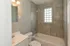 Bright and modern bathroom featuring elegant grey tiles, a chic vanity, and a stylish bathtub.