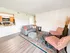 Inviting living room with modern decor, featuring a cozy gray sofa, vibrant patterned chairs, and an elegant rug, adjacent to a welcoming open kitchen.