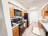 Inviting galley kitchen featuring modern appliances, warm wood cabinetry, and stylish floor tiling.