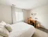 Bright and cozy bedroom with elegant decor, featuring a large window, plush bedding, and a stylish wooden desk.