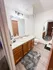 Elegant bathroom with a large mirror, chic lighting, wooden vanity, and plush rugs on sleek wooden flooring.