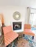 Elegant living room with patterned orange chairs, stylish fireplace, and decorative mirror enhancing cozy ambiance.