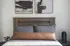 Contemporary bedroom with a stylish wooden headboard, cozy gray and brown pillows, and modern abstract wall art.