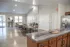 Elegant community room with modern kitchen island, long dining tables, and bright, airy atmosphere.