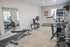 Modern apartment gym with state-of-the-art equipment, including a treadmill, elliptical, stationary bike, and free weights, in a bright and spacious setting.