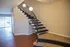 Inviting interior featuring a modern spiral staircase with elegant lighting, leading to a bright living area with stylish wood flooring and sliding glass doors.