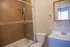 Inviting bathroom with elegant brown tile design, featuring a chic vanity, modern shower, and natural light through a window.