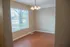 Bright, inviting room with large window and elegant light fixture, featuring hardwood floor and soft beige walls, perfect for a cozy dining or living area.