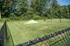 Inviting fenced grassy area surrounded by lush trees, perfect for outdoor activities and relaxation.