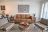 Chic living room featuring a stylish brown leather sofa, modern artwork, and rustic wooden coffee table, creating a cozy and elegant ambiance.