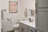 Modern bathroom with elegant fixtures, featuring a sleek vanity, chic abstract wall art, and contemporary cabinetry.