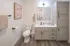 Elegant bathroom with modern fixtures, cozy lighting, and stylish cabinetry. Features a marble countertop and contemporary wall art.