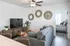 Chic and cozy living room with modern gray sofa, elegant wall decor, and large TV, leading to a bright bedroom with stylish decor.