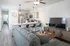 Modern open-concept living room and kitchen with sleek decor, large TV, and inviting gray sofa, perfect for relaxation and entertaining.
