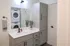 Modern bathroom with sleek gray cabinetry, marble countertop, and in-unit stacked washer and dryer for convenience.