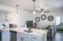 Elegant modern living space featuring open-concept kitchen with marble countertops, cozy living area, stylish decor, and view into a bright bedroom.