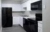 Modern kitchen with sleek black appliances, elegant white cabinetry, and stylish countertops, perfect for contemporary living.
