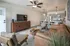 Chic and modern open-concept apartment living area featuring a cozy leather sofa, stylish armchairs, and a sleek wooden TV console with a flat-screen TV. The space flows into a contemporary kitchen with stainless steel appliances and elegant bar seating under pendant lights.