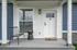 Charming front porch with a stylish bench, welcoming doormat, and pristine white door in a blue siding exterior.