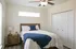 Bright and cozy bedroom featuring a comfortable bed with a navy throw, modern nightstand, and ample natural light from the window above.