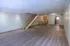 Modern open-concept living space with elegant hardwood flooring and a central staircase, leading to a bright kitchen area.